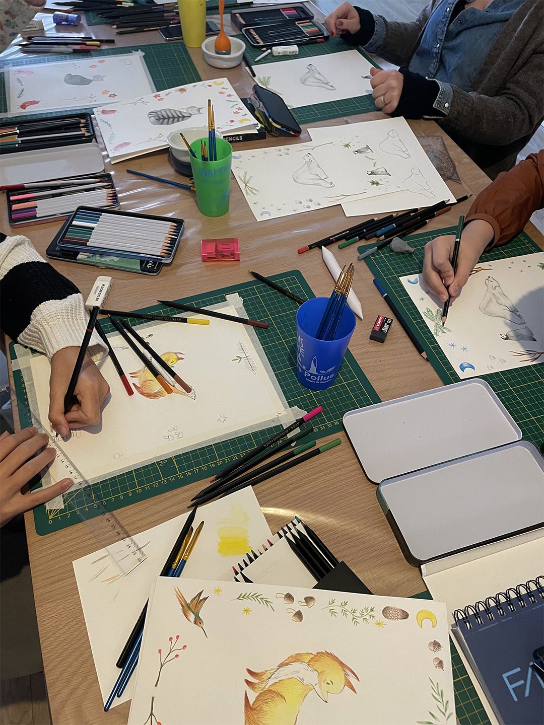 Élèves de l'atelier en train de dessiner autour de la grande table